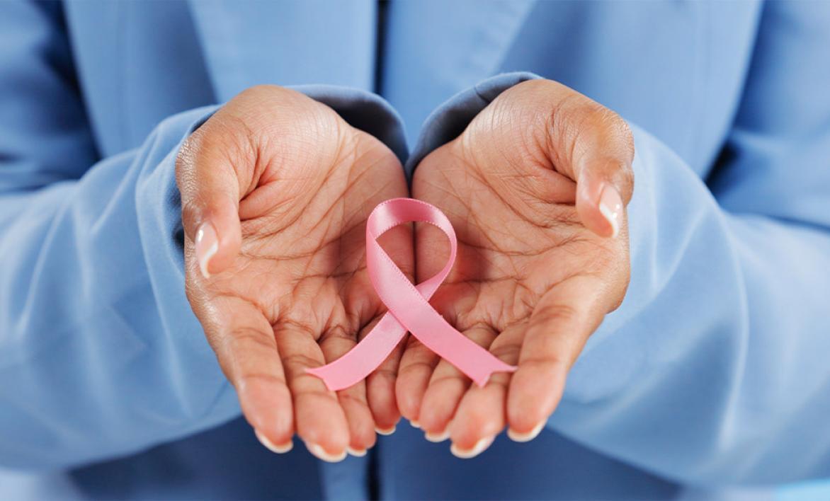 Deux main portant la broche à ruban rose.