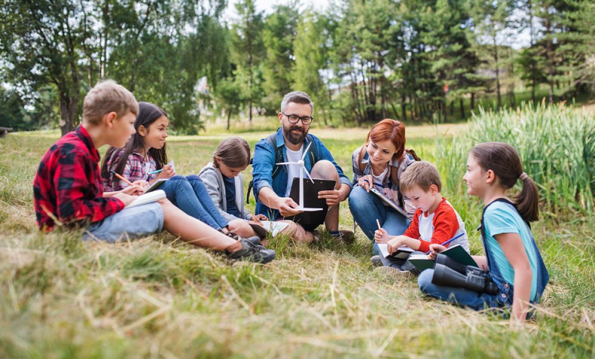 5 enfants et 2 adultes dans un champs observant la nature.