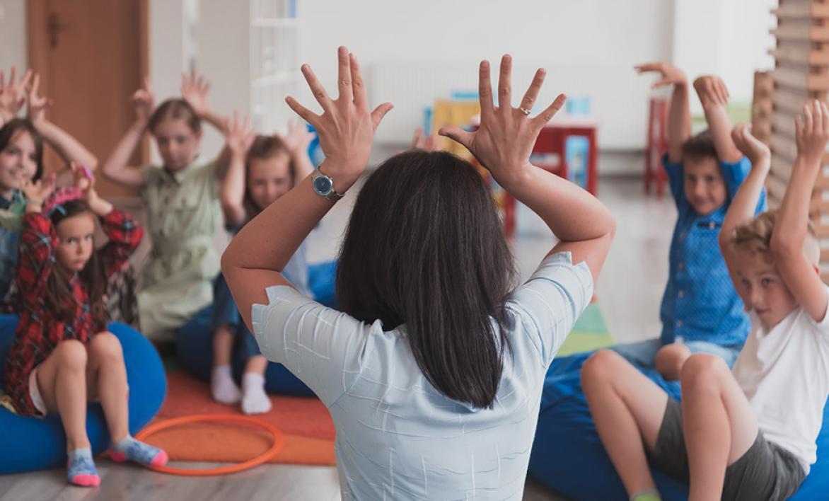 Une femme de dos jouant avec des enfants.
