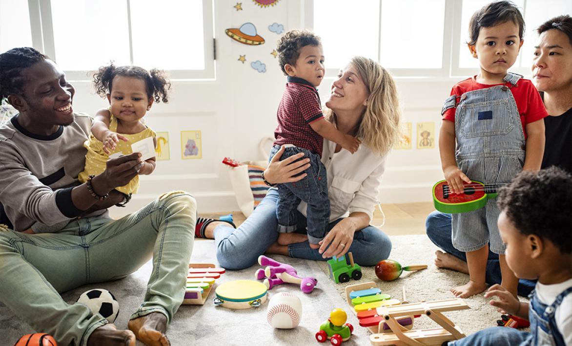Deux adultes et des enfants dans une salle avec des jouets.
