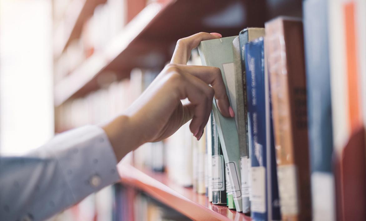 Main prenant un livre dans une bibliothèque 