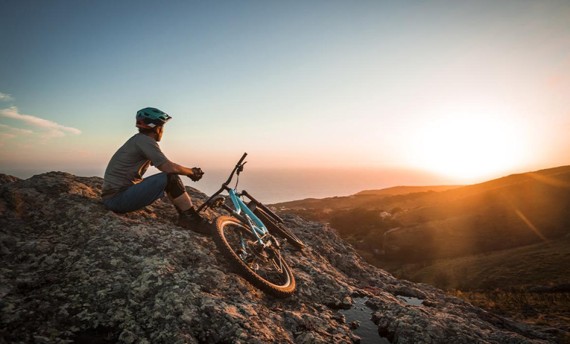 Un homme en haut d'une colline avec un vélo.