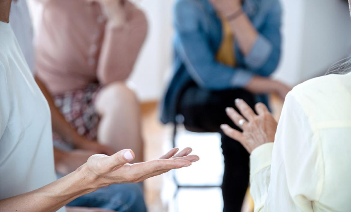 Des personnes discutant avec des mains en premier plan.