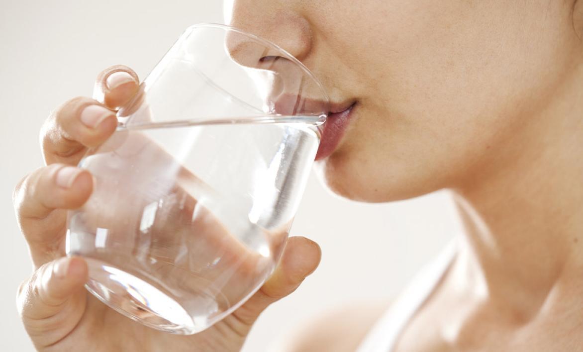 Une femme buvant un verre d'eau.