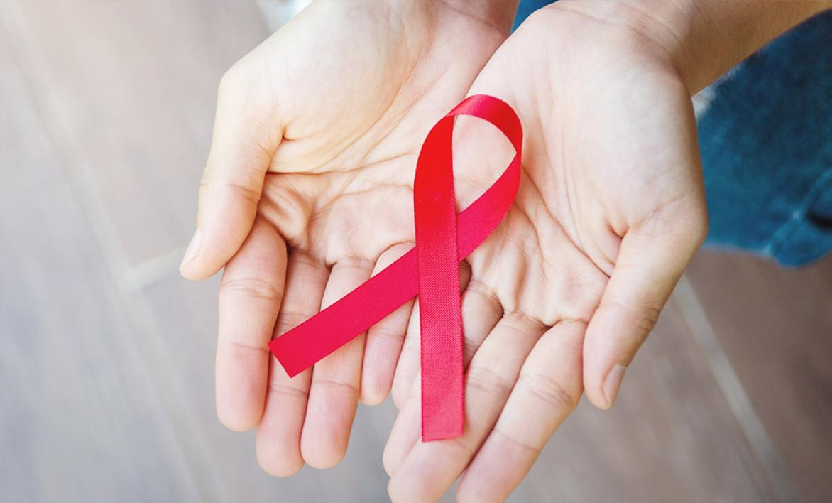 Deux mains tenant la broche à ruban rouge.