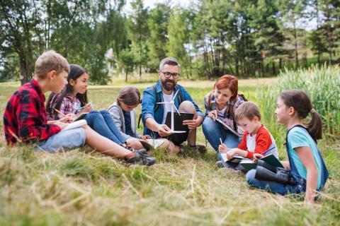 5 enfants et 2 adultes dans un champs observant la nature.