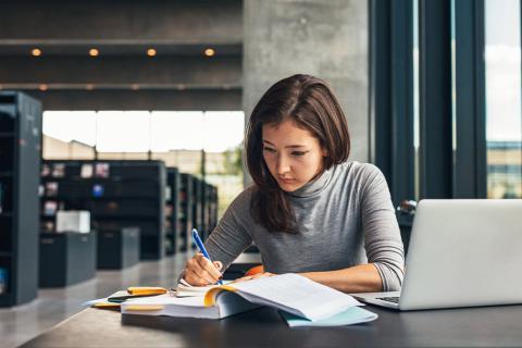 Jeune femme étudiant à la bibliothèque.