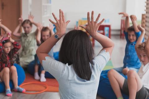 Une femme de dos jouant avec des enfants.