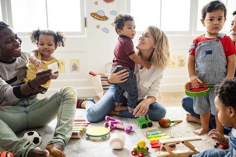 Deux adultes et des enfants dans une salle avec des jouets.