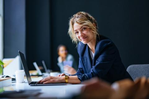 Une femme souriante devant un ordinateur.