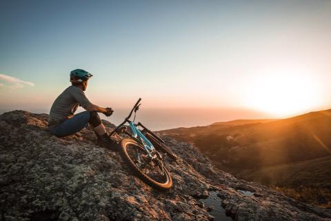 Un homme en haut d'une colline avec un vélo.