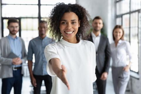 Une jeune femme tendant la main avec un groupe en arrière plan.