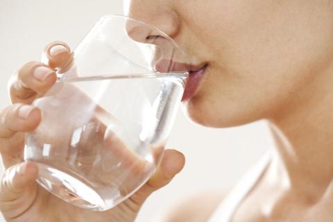 Une femme buvant un verre d'eau.