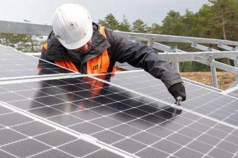 Un homme installant un panneau photovoltaïque.