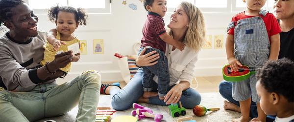 Deux adultes et des enfants dans une salle avec des jouets.
