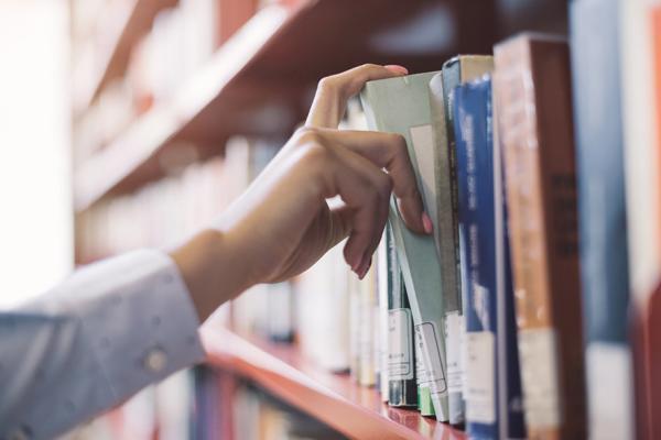 Main prenant un livre dans une bibliothèque 